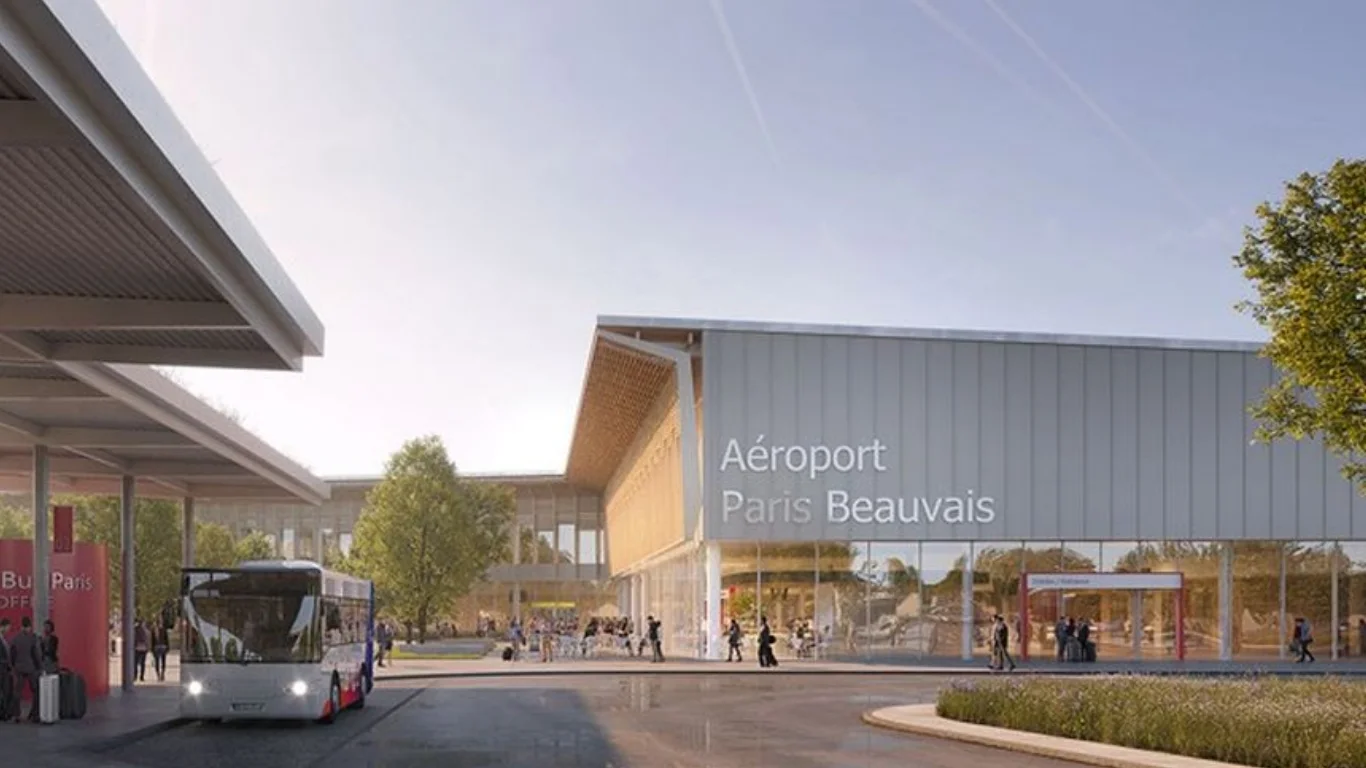 Vue extérieure de l'entrée principale du terminal de l'aéroport Paris Beauvais (BVA) avec navettes.